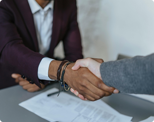 Two people shaking hands over a signed document